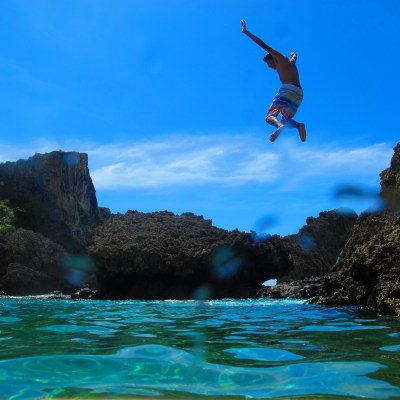 A man jumping off a cliff into the water