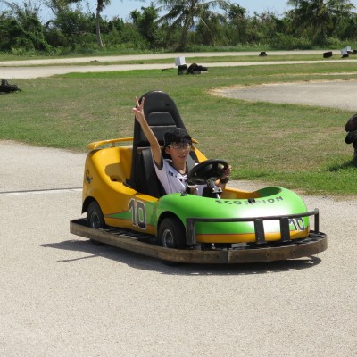 A kid giving the peace sign while driving a go kart