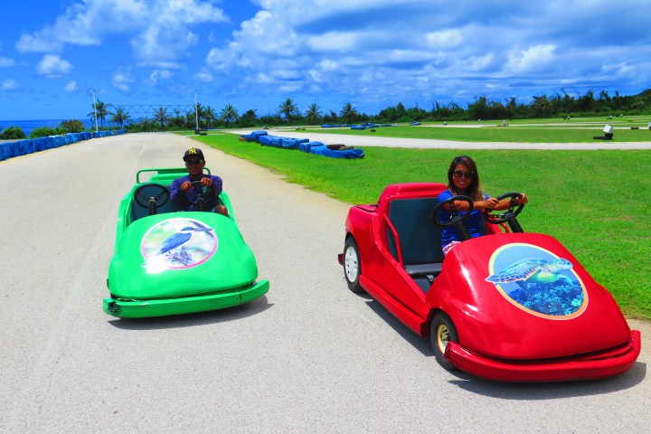A man and a woman behind the wheel of their go karts
