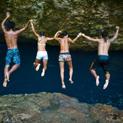A group of guests hold hands as they jump in the the grotto