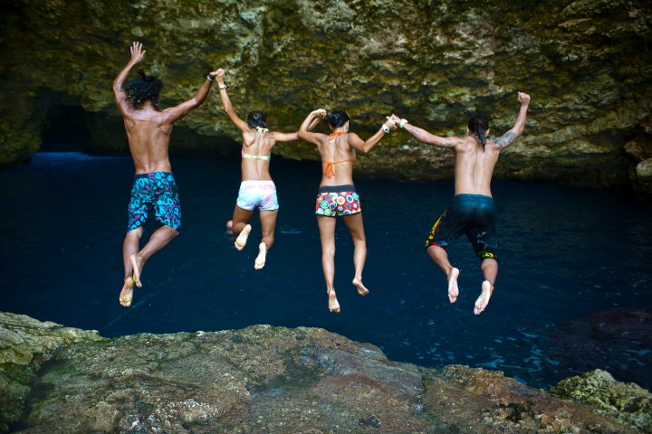 A group of guests hold hands as they jump in the the grotto
