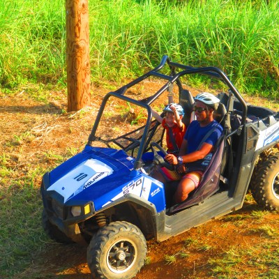 A kid with his arms raised as he enjoys his ride in a buggy