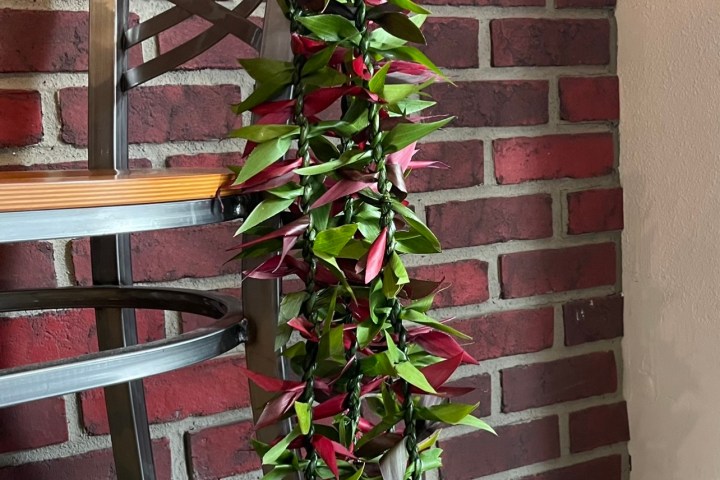 Chair with a green and red leaf garland draped over it against a brick wall.